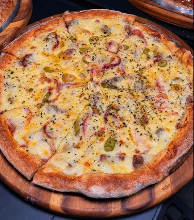 Pizza grande da Moriá fatiada, com muçarela gratinada, azeitonas e orégano